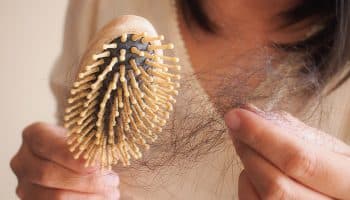 Woman holding strands of hair that are stuck to a brush