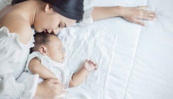 Close up image of a mother and her newborn baby sleeping in a bed together