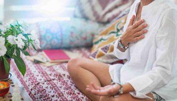 A woman meditating while putting a hand on her chest