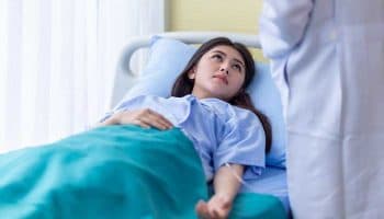 Asian woman with ectopic pregnancy is consoled by a doctor