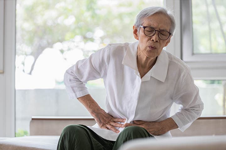 Sick elderly Asian man with belly pain with hands on his abdomen