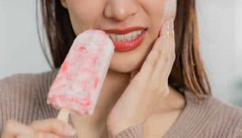 Woman looking uncomfortable while eating an ice-cream.