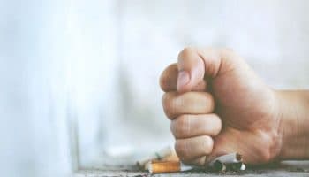 A man using his fist to crush cigarettes