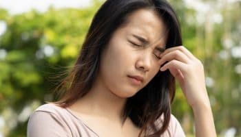 Woman closing her eyes tightly while leaning a few fingers on her left eyelid