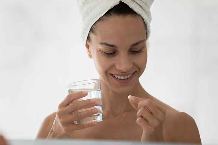 happy woman holding pill and glass