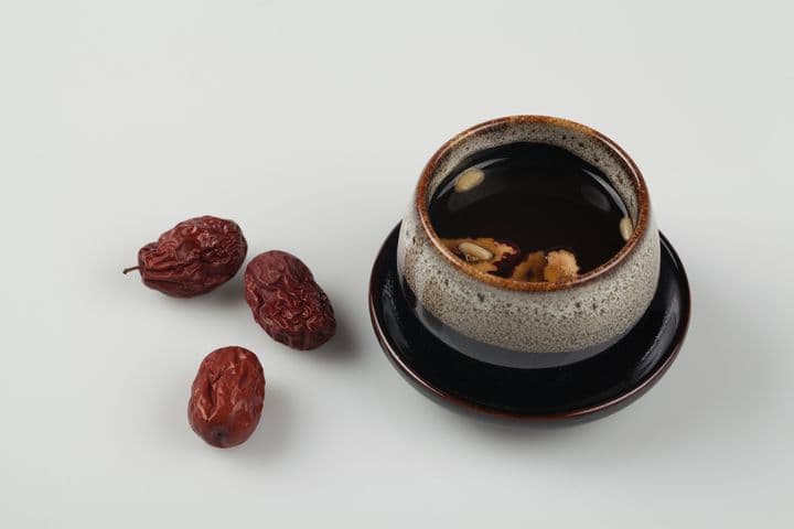 Dried jujubes next to a cup of tea