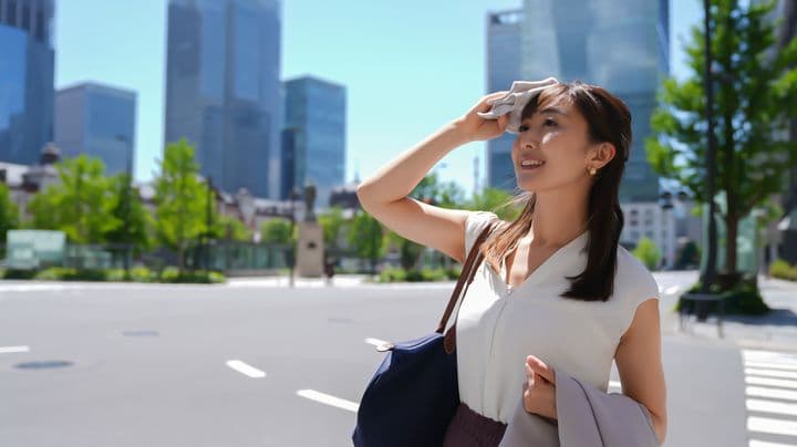 A business woman wiping sweat from her face in the n the hot weather