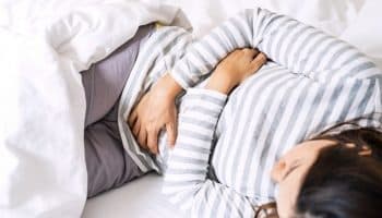 A young woman touching her stomach with her hands due to period cramps