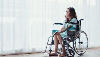 Woman sitting on a wheelchair with mobile in hand