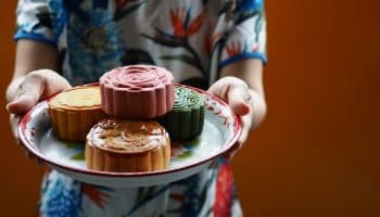 Woman serving various types of mooncakes on a metal tray