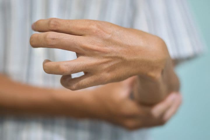 Man squeezing his left forearm 