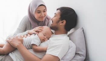 A couple holding their newborn baby in bed