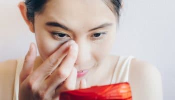 Woman applying concealer under her eyes to mask dark eye bags