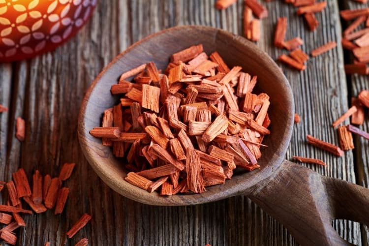 Wooden spoon containing chopped sandalwood.