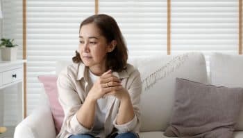 Mature woman sitting on a chair and looking down.