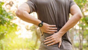 A man feeling back pain and using his hands to support his injury.