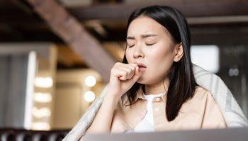 A woman coughing at her fist.