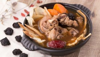 Chinese herbal chicken soup prepared with various herbal ingredients in a black-coloured clay pot.