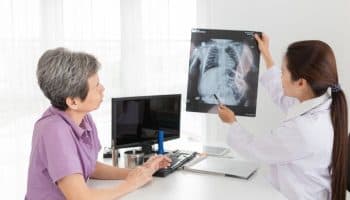 A woman looking on as a clinical specialist explains the findings of an X-ray image to her.