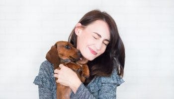 A happy woman holding a small dog