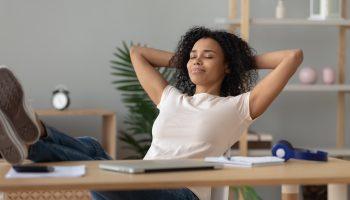 Calm African-American girl holding hands sits at home office enjoy peace of mind