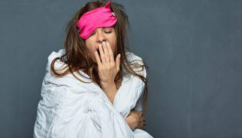 Portrait of yawning woman waking up isolated on grey wall background