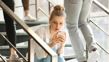 A woman sitting on a staircase while looking at her phone