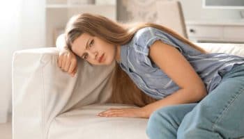 A young woman resting her head on a sofa as she was feeling gerd symptoms