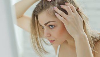 A woman checking at her hair and scalp in the mirror to avoid hair loss in women