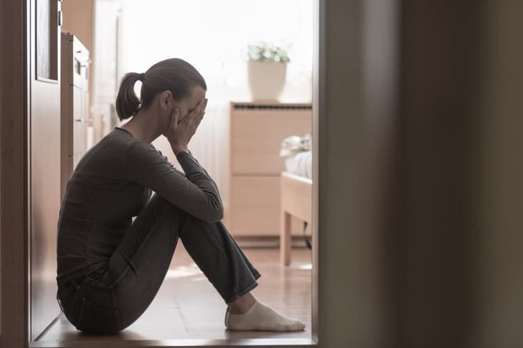 A woman with anxiety sitting with her head in her hands