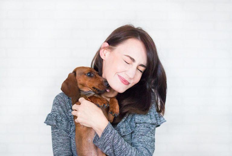 A happy woman holding a small dog