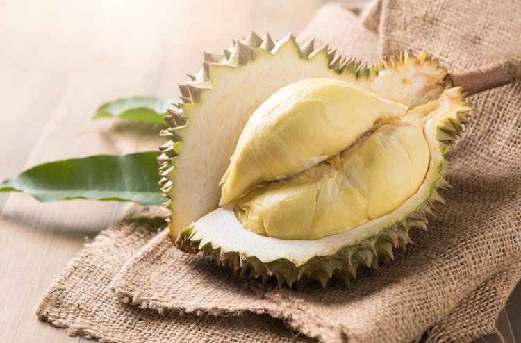 An image of whole durian fruit sliced open 