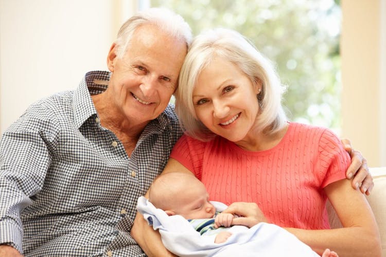 Smiling grandparents holding a new baby