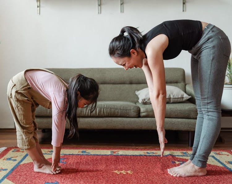 A mother and daughter exercising together indoors.